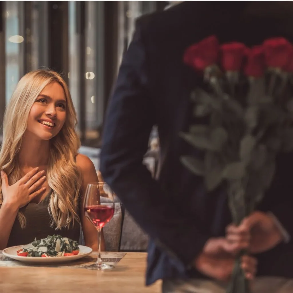 beautiful woman with blonde hair being surprised by a man with red roses