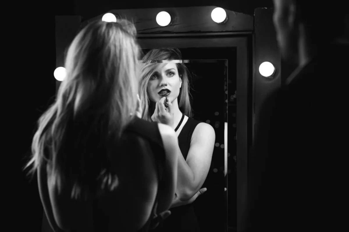 woman applying lipstick in mirror