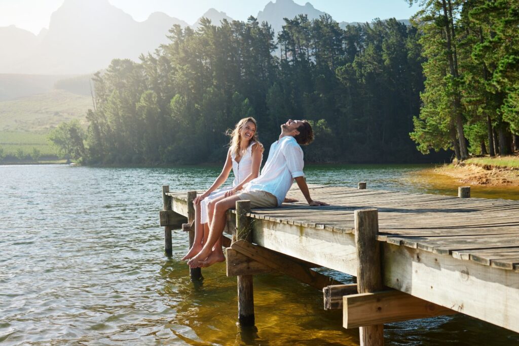 smiling loving couple sitting on pier and talking